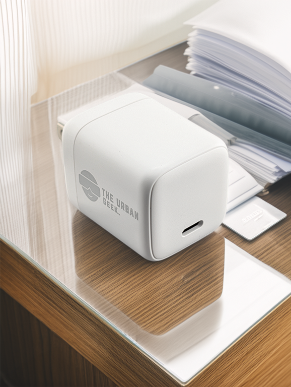 White 30W power adapter on a wooden surface with 'The Urban Geek' branding.